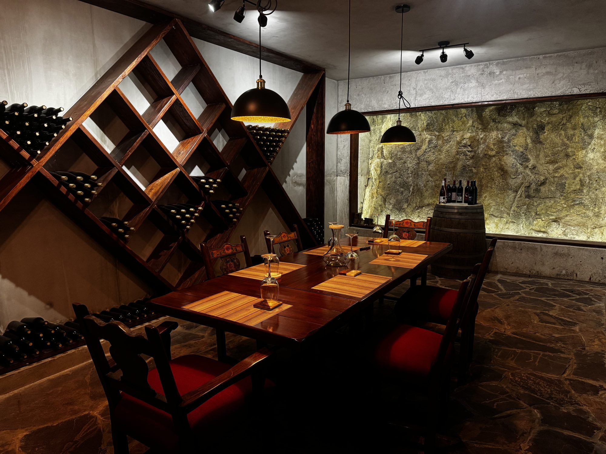 Cava privada de Macklish con racks de madera en diamante, muro de piedra y mesa de catas